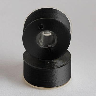 Two bobbins with black thread, stacked.