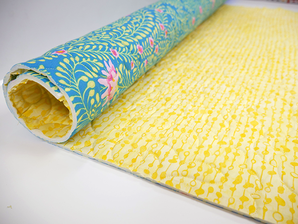 Sample of  yellow and floral fabric quilted around Sew Any Shape Foam, partially rolled up