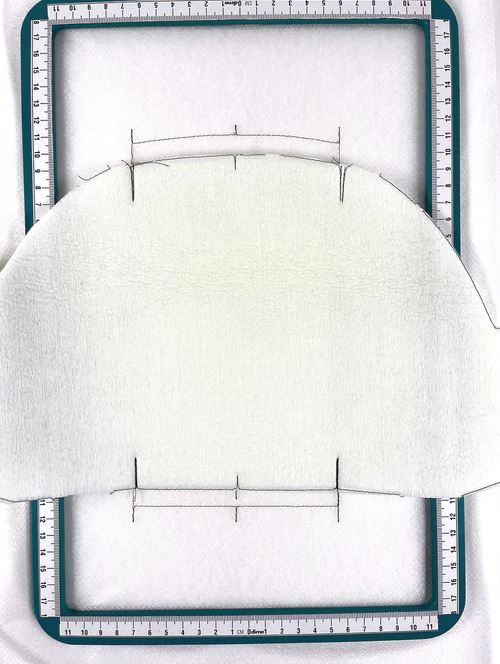 stitched and trimmed piece of foam laid over the magnetic hoop, which holds a stitched base layer
