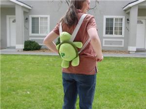 Woman wearing stuffed turtle backpack.